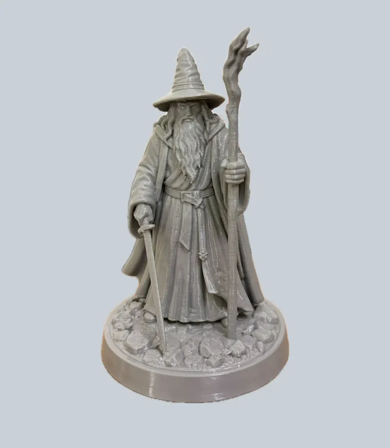 Grey figurine of an old wizard in a pointed hat holding a staff